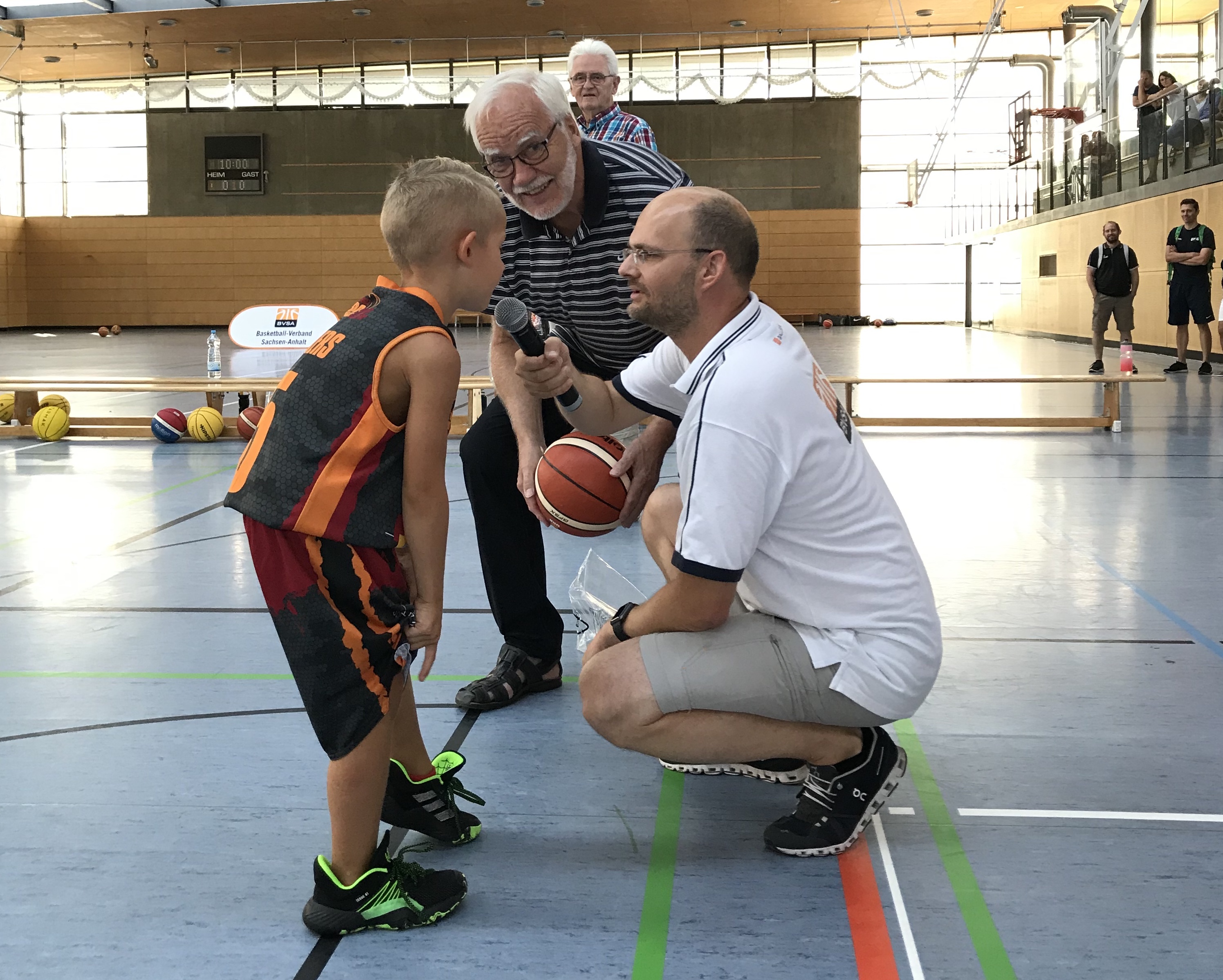"Club der Freunde des Basketball"-Präsident Heinz-Michael Sendzik (Mitte) übergibt gemeinsam mit Thomas Schaarschmidt, BVSA-Vorsitzender (rechts), dem jüngsten Spieler des Turniers einen Basketball. // Foto: BVSA